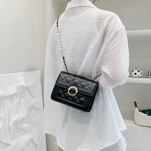 Quilted black crossbody bag with pearl chain and gold hardware worn by a model