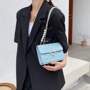 Light blue quilted crossbody bag with pearl chain and elegant ring buckle on model