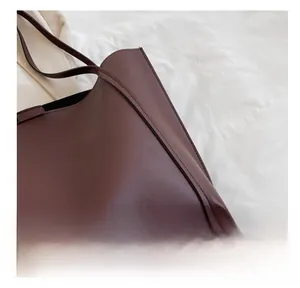 Detail of neat stitching on a large dark reddish-brown matte leather tote bag
