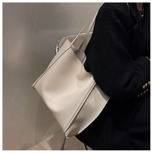 Detail of minimalist beige PU leather tote bag with slim shoulder straps on a model