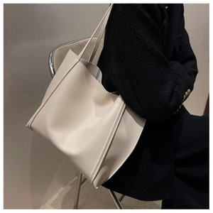 Detail view of a minimalist cream tote bag showing smooth matte texture and side piping