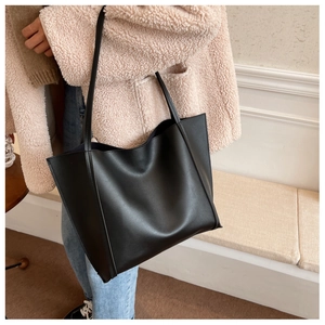 Lifestyle shot of a black oversized tote bag with long straps on a pink plush jacket
