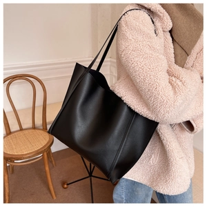 Detailed close-up of large black leather tote bag with fine stitching and matte texture