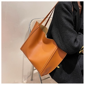 Side view of a spacious caramel tote bag worn with a black coat for urban style