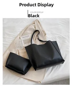 Detailed view of the black PU leather tote bag with matching pouch on a bed