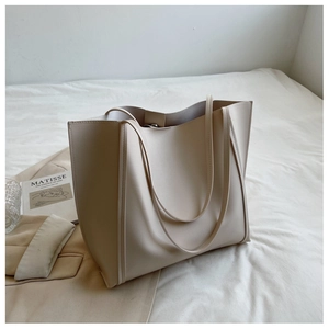 Detail of a large cream leather tote bag arranged with a Matisse art book on white fabric