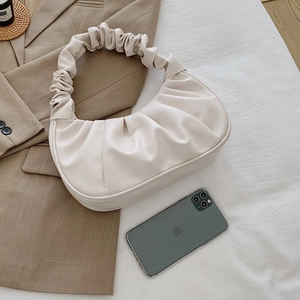 Detail view of cream pleated crescent bag with cloud handle and iPhone for size reference