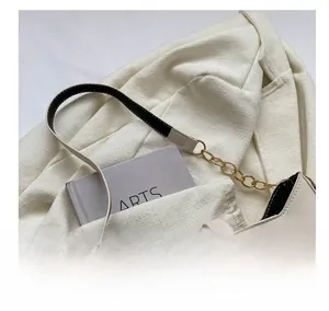Detail of minimalist cream PU leather shoulder bag with chain strap on beige blazer