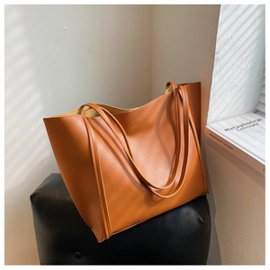 Detailed view of the brown matte PU leather tote bag on a stool with natural light