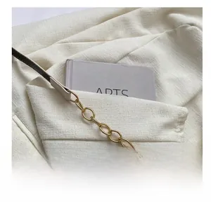 Detailed close-up of a minimalist cream shoulder bag with elegant gold metal chain links