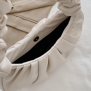 Close-up of off-white pleated bag with magnetic buckle and soft faux leather texture