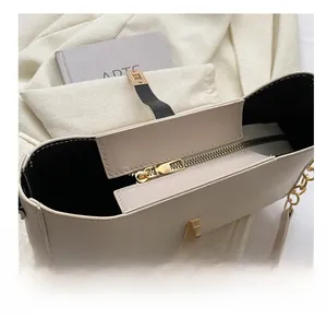 Close-up of smooth metal zipper and turn-lock clasp on a beige textured leather bag