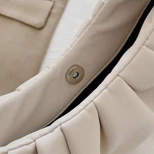Macro shot of silver magnetic clasp on cream-white pleated leather handbag detail