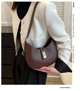 Sac sous le bras vintage marron avec fermoir doré porté par un mannequin en veste tweed