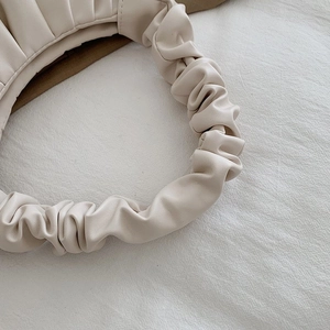 Close-up of pleated handbag handle and soft cream leather texture for modern ladies