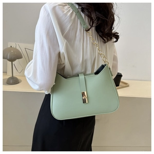 Detail of mint green underarm bag with gold chain strap and metal turn-lock closure