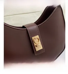 Détail du sac sous l'aisselle en cuir marron foncé vintage avec fermoir doré