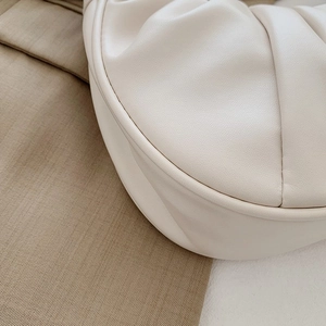 Detail shot of cream pleated handbag showing premium leather texture and stitching