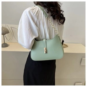 Detail of mint green half-moon underarm bag with gold chain strap and metal clasp