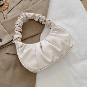 Detailed macro shot of the cream pleated PU leather surface and soft hobo bag handle