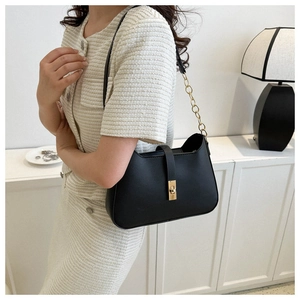 Close-up of black PU leather underarm bag with gold twist lock on a beige outfit