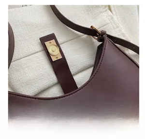 Gros plan sur la boucle magnétique dorée et les coutures de ce sac en cuir marron