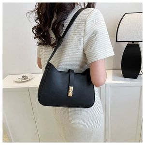 Detail of black matte underarm bag featuring a refined gold metallic twist lock closure
