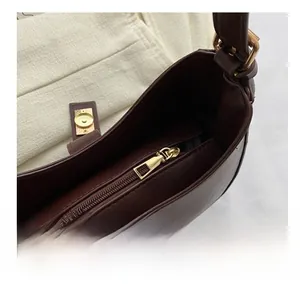 Détail de la fermeture éclair dorée sur le sac à bandoulière en cuir marron foncé