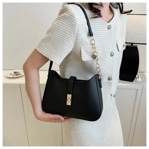 Detail of black faux leather shoulder bag with gold twist lock and chain strap