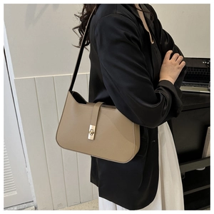 Detail of minimalist beige leather underarm bag featuring a golden square twist lock