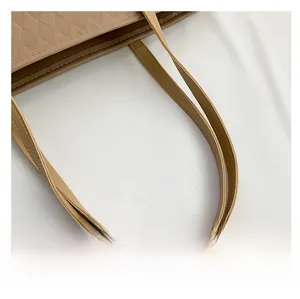 Detail of beige quilted tote bag showing double-stitched leather handle and diamond texture