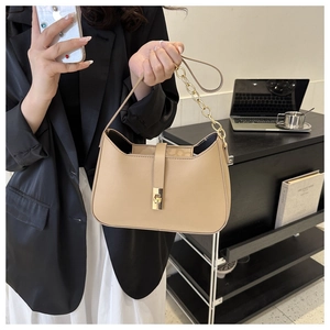 Detail of beige leather shoulder bag featuring metal chain strap and sleek metal lock closure
