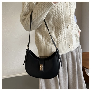 Détail d'un sac hobo noir avec fermoir doré rectangulaire et bandoulière en similicuir lisse
