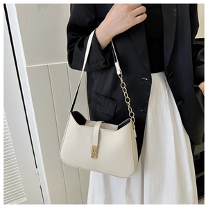 Close-up of minimalist white shoulder bag with gold square buckle and chain strap on model
