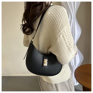 Sac bandoulière demi-lune en cuir noir minimaliste avec boucle dorée sur un modèle