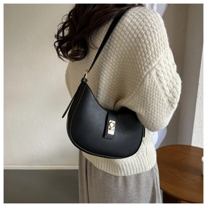 Détail d'un sac hobo en cuir noir avec boucle dorée et design minimaliste et élégant