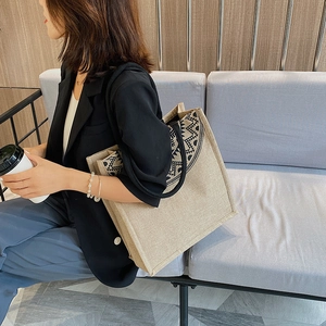 Detail of beige linen tote bag with black geometric pattern and rope handles