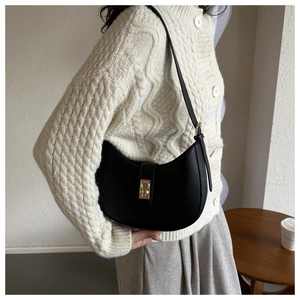Détail d'un sac porté épaule demi-lune noir avec boucle dorée sur fond de style minimaliste