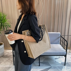 Close-up of linen tote bag with black tribal geometric pattern held by a model