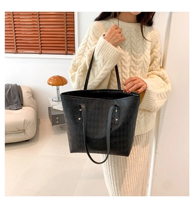 Close-up of black quilted PU leather tote bag worn by model in cozy home setting