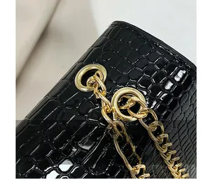 Close-up of golden metal chain link and buckle on black crocodile pattern bag