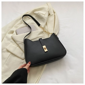 Detail of black cat-ear shaped underarm bag with gold metal buckle on white blazer