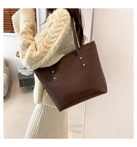Detail of dark brown quilted tote bag with gold rivet studs and elegant autumn outfit
