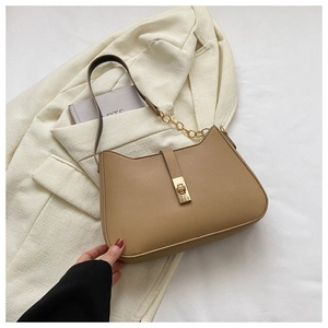 Detail of camel cat-ear handbag with golden buckle and chain strap on cream blazer