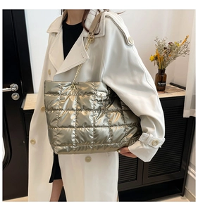 Detail of champagne gold quilted tote bag with metallic chain strap and deer charm