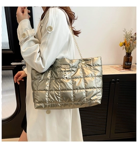 Detail of gold quilted tote bag with metal chain strap and deer charm on model