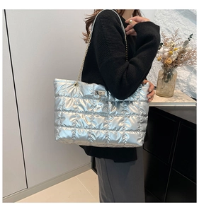 Detail of silver metallic quilted tote bag with gold chain strap and deer pendant accessory