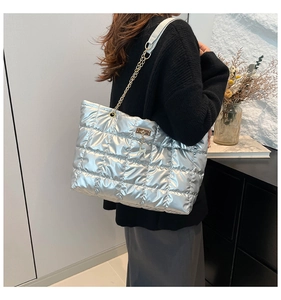 Macro view of silver quilted puffer tote bag with metal chain strap and deer charm detail