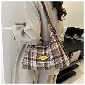 Close-up of retro plaid wool shoulder bag featuring a gold emblem and chain strap