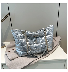 Close-up of silver quilted tote bag with metallic finish and gold deer pendant detail